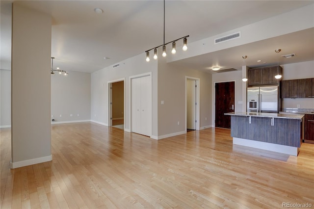 kitchen featuring high quality fridge, visible vents, open floor plan, light wood-type flooring, and a center island