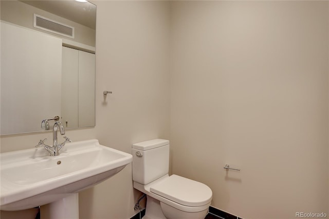 half bathroom featuring visible vents, a sink, and toilet