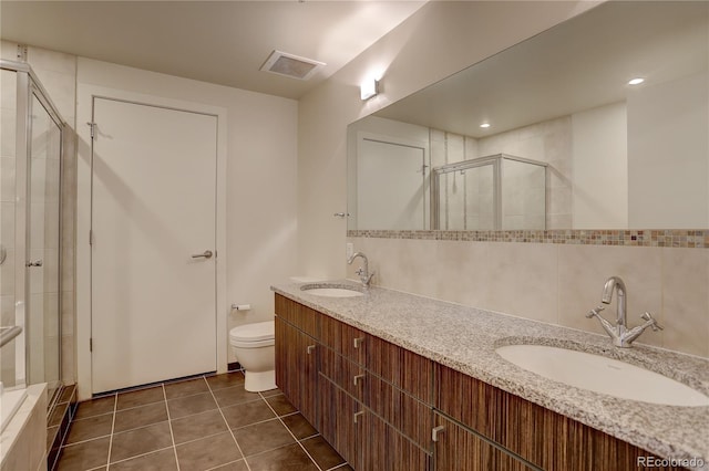 full bath with toilet, a stall shower, tile patterned flooring, and a sink