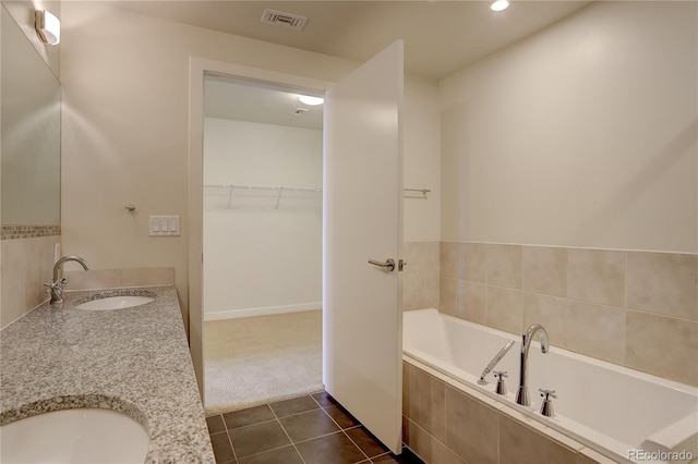 full bathroom with a walk in closet, a garden tub, visible vents, a sink, and tile patterned flooring