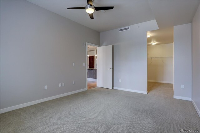 unfurnished bedroom featuring baseboards, a spacious closet, visible vents, and light colored carpet