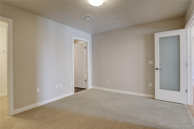 carpeted spare room with visible vents and baseboards