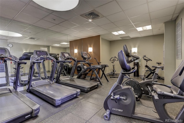 exercise room featuring a paneled ceiling, visible vents, and baseboards