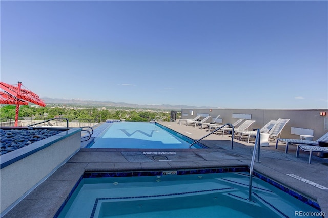 community pool featuring a patio area, fence, and a mountain view