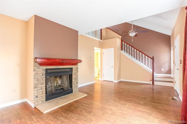 19421 E Milan Cir, Aurora, CO 80013 - unfurnished living room featuring a fireplace with raised hearth, wood finished floors, stairs, baseboards, and high vaulted ceiling