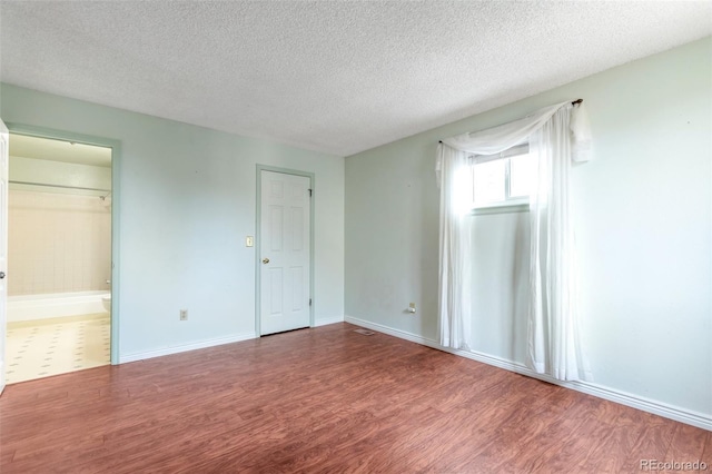 19421 E Milan Cir, Aurora, CO 80013 - unfurnished bedroom featuring wood finished floors, a textured ceiling, baseboards, and connected bathroom