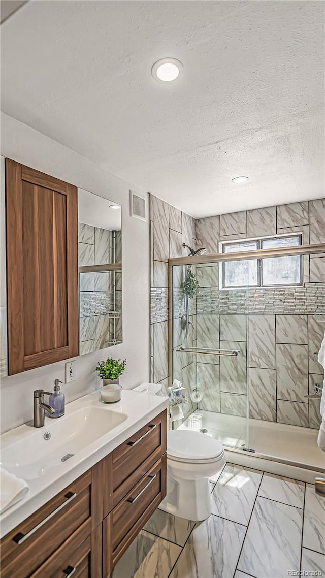 bathroom with a textured ceiling, an enclosed shower, vanity, and toilet