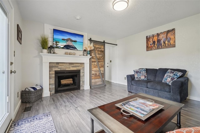 living room with hardwood / wood-style flooring, a fireplace, a barn door, and a textured ceiling