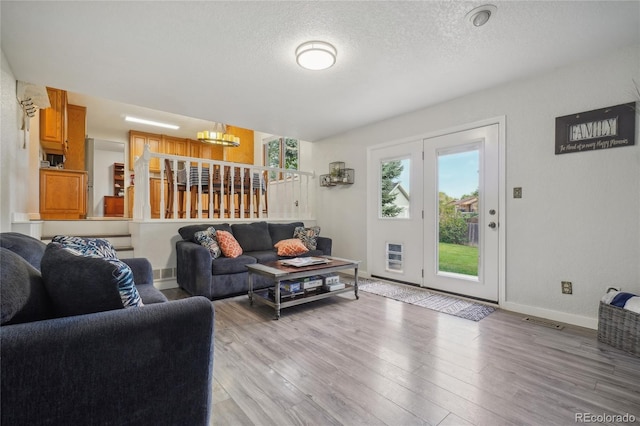 living room featuring heating unit, light hardwood / wood-style floors, a textured ceiling, and a chandelier