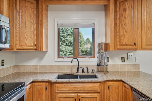 kitchen featuring light stone countertops, appliances with stainless steel finishes, and sink