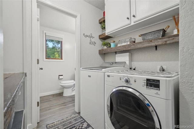 laundry room with cabinets, light hardwood / wood-style flooring, and washer and dryer