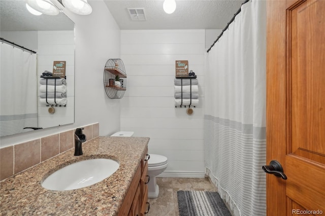 bathroom featuring vanity, toilet, a textured ceiling, and wooden walls