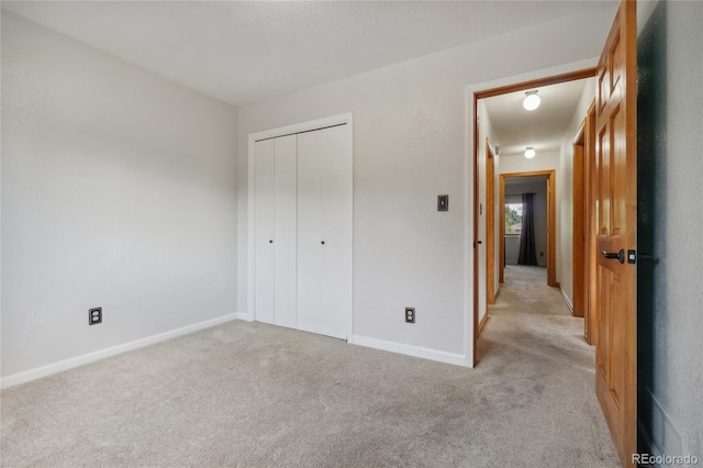 unfurnished bedroom featuring light carpet and a closet