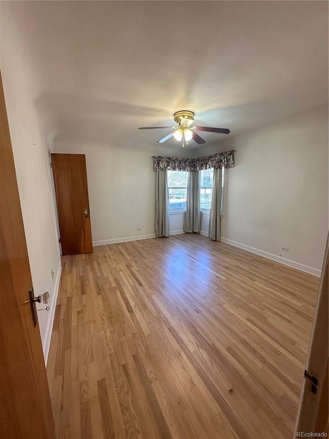 spare room featuring light wood finished floors, baseboards, and ceiling fan
