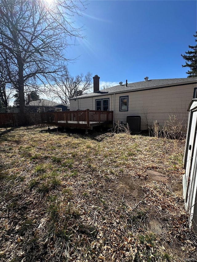view of yard featuring central AC, fence, and a deck