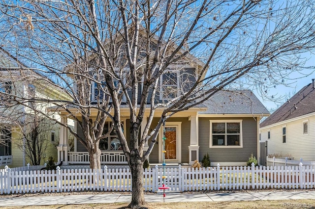 view of front of property with roof with shingles, a porch, and a fenced front yard