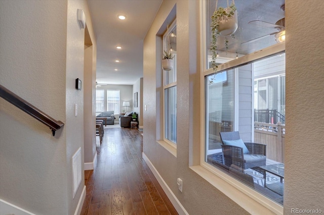 corridor with dark wood finished floors, recessed lighting, visible vents, a textured wall, and baseboards