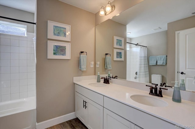 bathroom featuring wood finished floors, a sink, baseboards, and double vanity