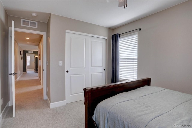 bedroom with baseboards, visible vents, a closet, and light colored carpet