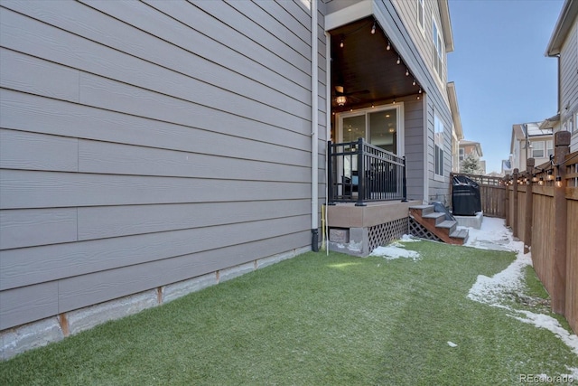 view of side of home with fence and a yard