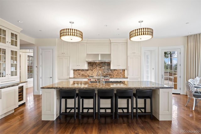 67 Indigo Way, Castle Rock, CO 80108 - kitchen featuring extractor fan, dark stone countertops, glass insert cabinets, decorative backsplash, and dark wood-style floors