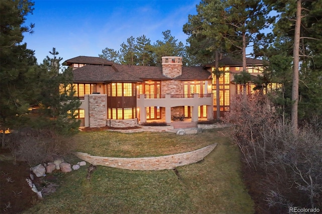 67 Indigo Way, Castle Rock, CO 80108 - rear view of house with a yard, stone siding, a patio area, a chimney, and a balcony