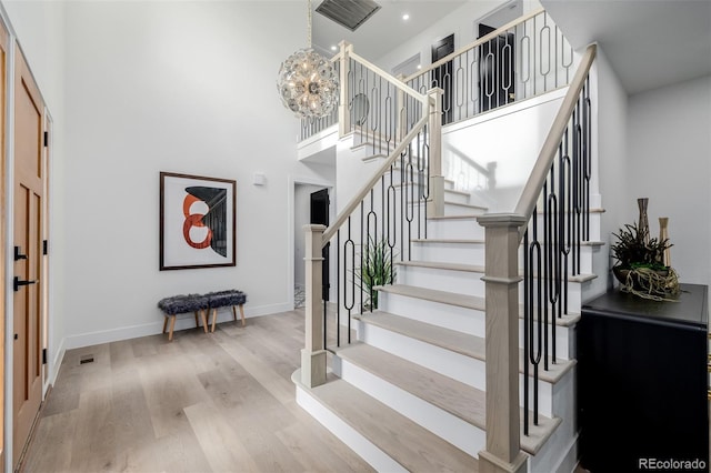 stairs featuring a towering ceiling, hardwood / wood-style floors, and an inviting chandelier