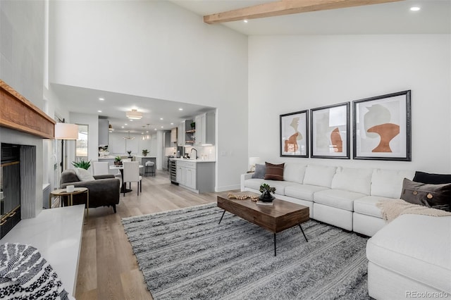 living room with high vaulted ceiling, light hardwood / wood-style floors, sink, and beamed ceiling