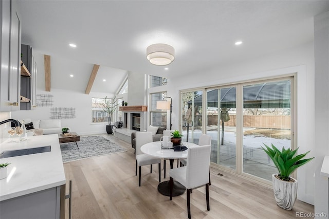 dining room featuring lofted ceiling with beams, light hardwood / wood-style floors, and sink