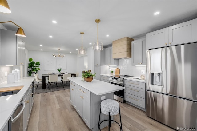 kitchen with pendant lighting, stainless steel appliances, light hardwood / wood-style floors, and a kitchen island