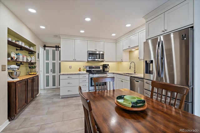 6936 S Knolls Way, Centennial, CO 80122 - kitchen with appliances with stainless steel finishes, a sink, a barn door, light tile patterned floors, and recessed lighting