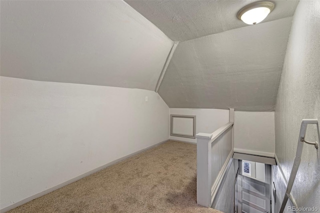 bonus room with vaulted ceiling, a textured ceiling, and carpet