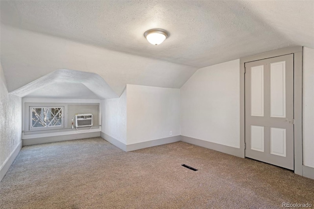 bonus room featuring light carpet, a wall mounted AC, vaulted ceiling, and a textured ceiling