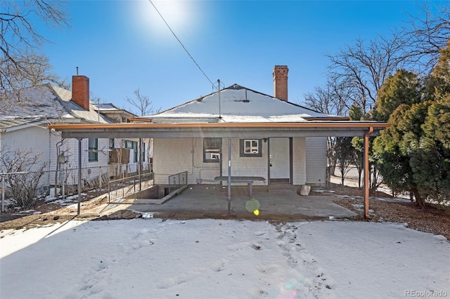 snow covered back of property with a porch