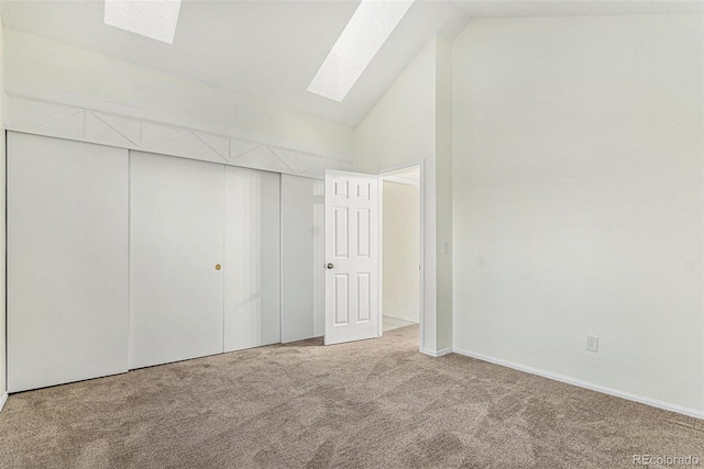 unfurnished bedroom with vaulted ceiling with skylight, a closet, and carpet flooring