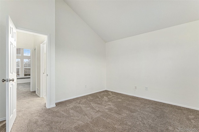 carpeted spare room with high vaulted ceiling