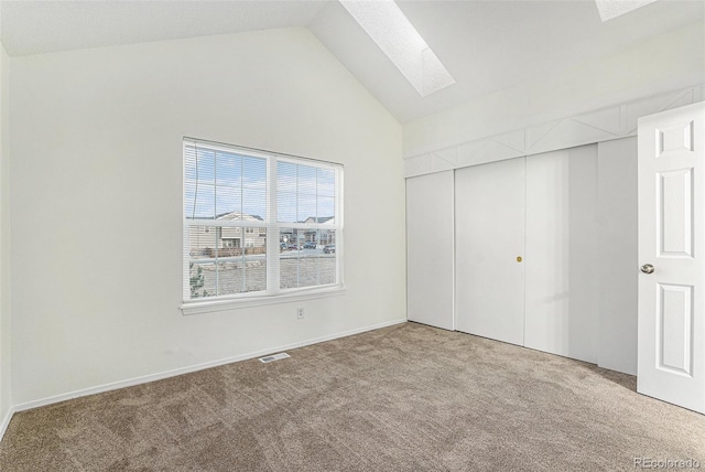 unfurnished bedroom with carpet flooring, a skylight, high vaulted ceiling, and a closet