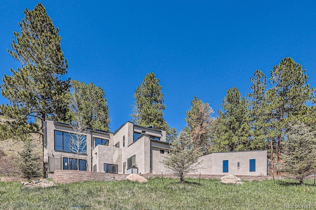 back of house featuring a yard, stucco siding, and a balcony