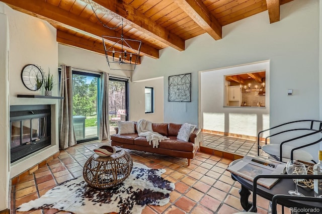 living room featuring an inviting chandelier, a glass covered fireplace, beam ceiling, wood ceiling, and tile patterned floors