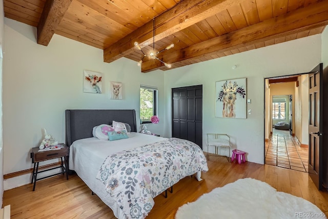 bedroom with beamed ceiling, wood ceiling, light wood-style flooring, and a closet
