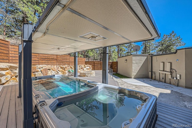 deck with a fenced backyard and an outdoor hot tub