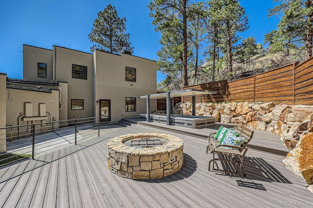 deck featuring an outdoor fire pit, fence, and a jacuzzi