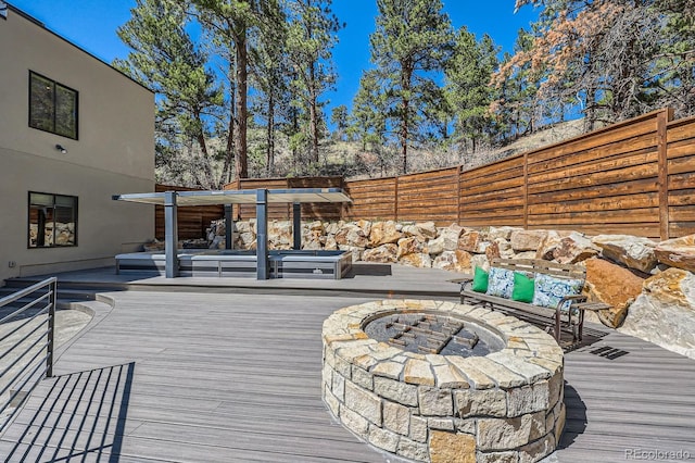 deck featuring fence, a hot tub, and a fire pit
