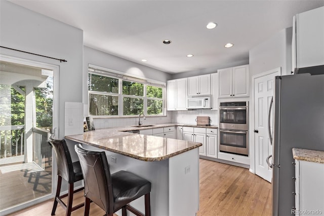 10345 Lions Heart, Lone Tree, CO 80124 - kitchen featuring stainless steel appliances, a peninsula, white cabinetry, tasteful backsplash, and recessed lighting