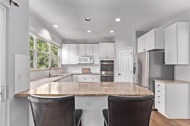 10345 Lions Heart, Lone Tree, CO 80124 - kitchen featuring stainless steel double oven, a peninsula, white microwave, tasteful backsplash, and recessed lighting