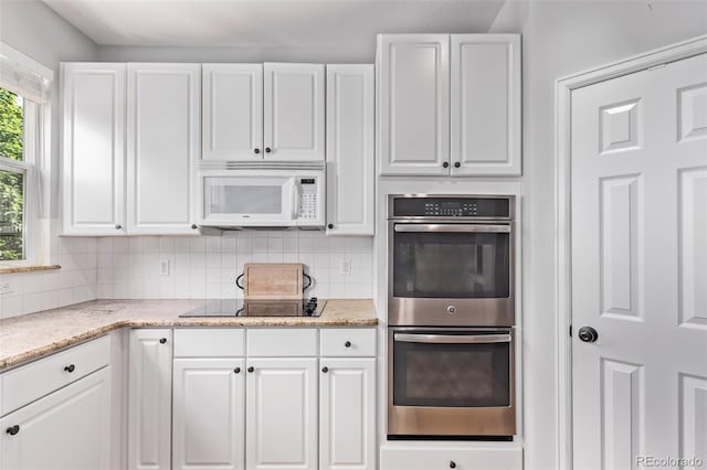 10345 Lions Heart, Lone Tree, CO 80124 - kitchen with stainless steel double oven, black electric stovetop, white microwave, white cabinetry, and backsplash