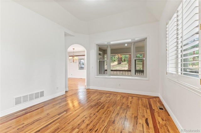 empty room with a notable chandelier and hardwood / wood-style floors