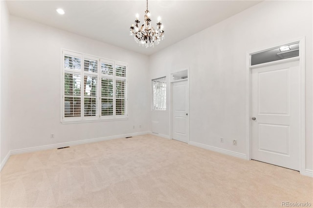 empty room with carpet flooring and an inviting chandelier