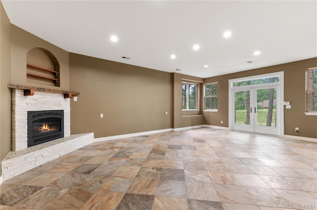 unfurnished living room with a stone fireplace, french doors, and light tile patterned floors