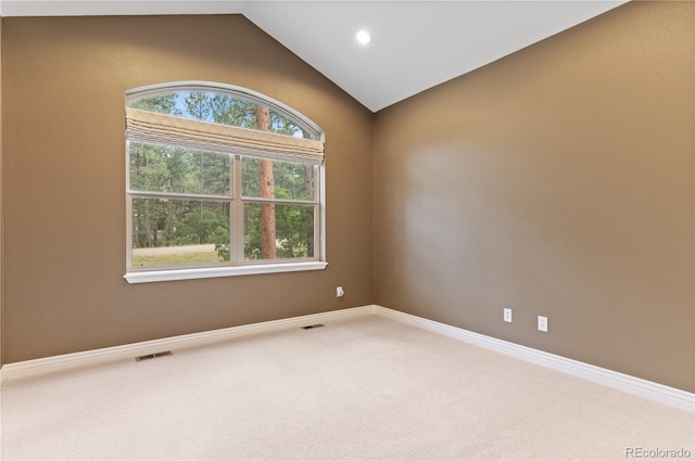 spare room featuring carpet flooring, a healthy amount of sunlight, and lofted ceiling